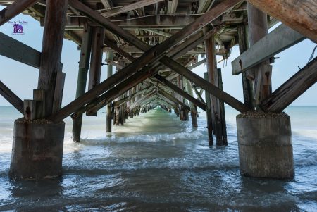 Shows the underneath of the long fishing pier in Redington beach Fl with a below view under the pier and crashing waves 