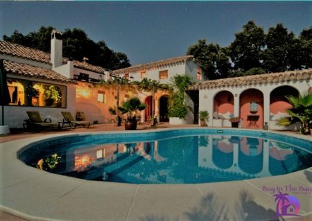Large mediterranean pool home lit up at night that is white with a tile barrel roof and shows a good example of Homes For Sale Sunset Park Tampa Fl