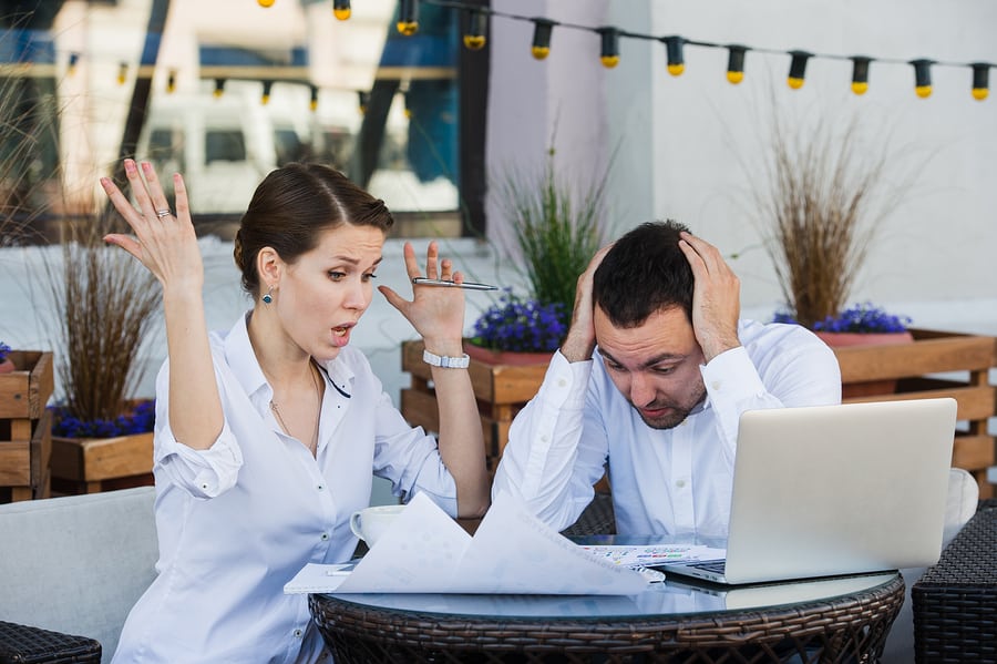 a couple in a serious argument negative emotion discussing using an ibuyer vs, a real estate agent at outdoor cafe