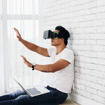 guy with 3d glasses sitting against a wall