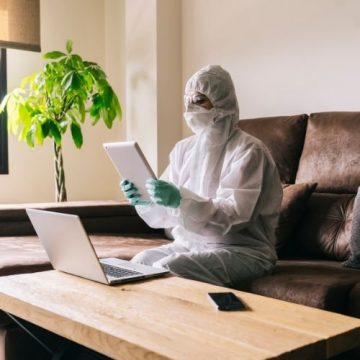 image of a woman in PPE and mask looking at a laptop