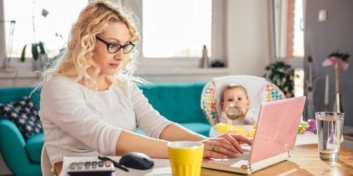 mother trying to work from home while feeding baby